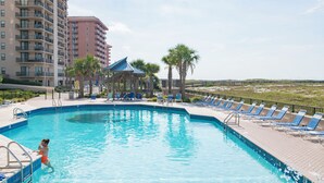 A swimming pool with lounge chairs and a gazebo, surrounded by high-rise buildings and palm trees. - Beachfront One Bedroom Sleeps Six (Orange Beach)
