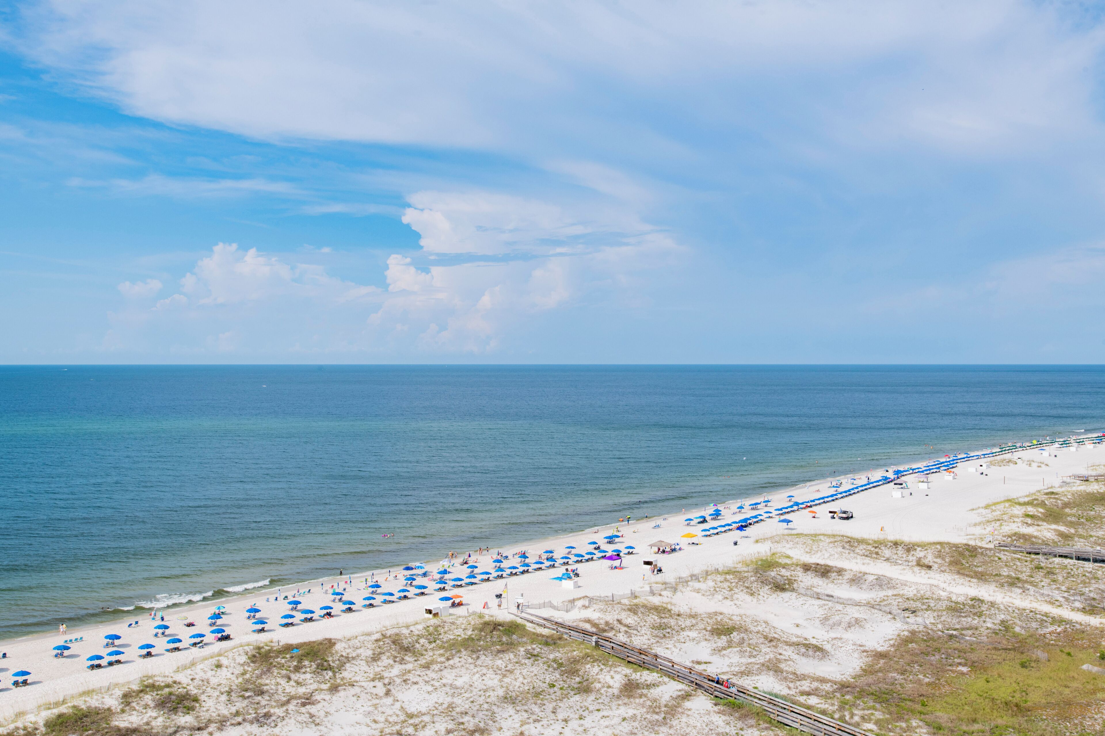 Een strand met rijen parasols en mensen.