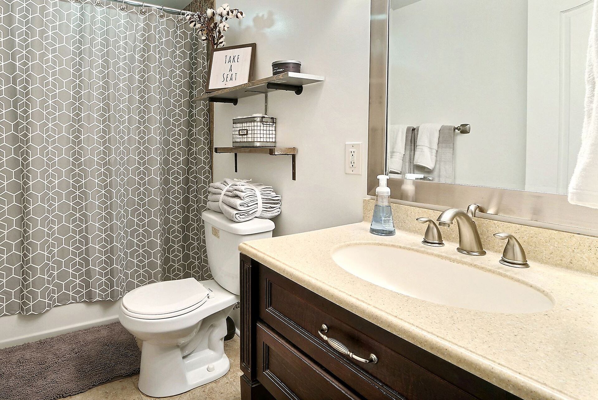 A bathroom with a toilet, a sink with a mirror, and a shower curtain with a geometric pattern.