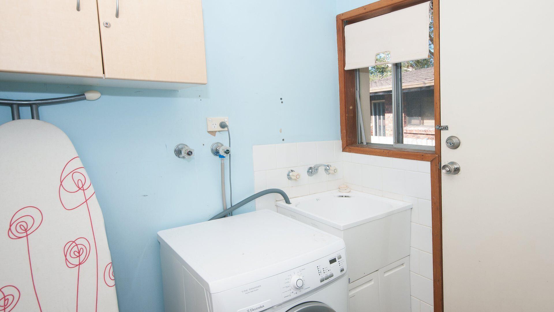 Un cuarto de lavandería con lavadora, secadora y lavamanos.