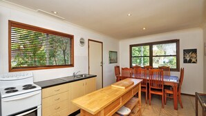 A compact kitchen with a stove, sink, and wooden dining table with chairs.