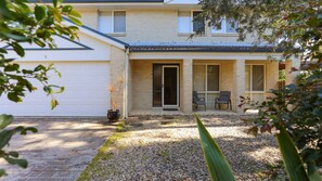 A two-story house with a covered patio, a garage, and a gravel driveway.