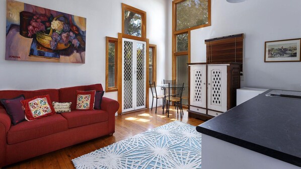 A living room with a red sofa, a glass table, and a white patterned rug.