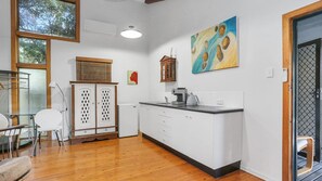 A compact kitchen with a wooden countertop, white cabinets, and a dining area with a glass table and chairs.