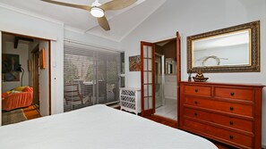 A bedroom with a bed, a dresser, a mirror, and a ceiling fan. - Bennett's Beach Cottage (Hawks Nest)