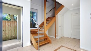 Un intérieur moderne avec un escalier en bois, une porte et une vue sur l’extérieur.