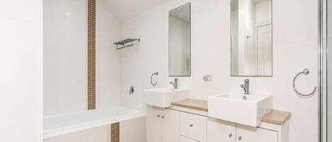 Une salle de bain moderne avec une baignoire, deux lavabos et un grand miroir.