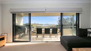 Un salon moderne doté d’une porte-fenêtre coulissante donnant sur un balcon avec vue sur la mer et les collines.