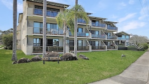 A multi-story residential building with balconies, a sign reading 'RIO VISTA,' and a well-maintained lawn.