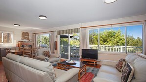 A spacious living room with a sofa set, a television, and a dining area with chairs and a table.