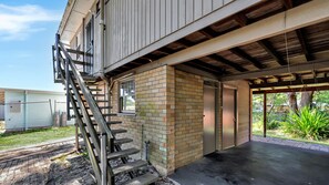 Un edificio con fachada de ladrillo, una escalera metálica y un área exterior cubierta.