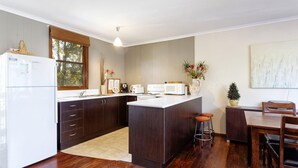 Une cuisine compacte avec des meubles de couleur bois foncé, un réfrigérateur blanc et un îlot central doté de tabourets.