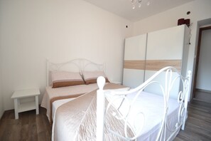 A bedroom with a white metal bed frame, a bedside table, and a wardrobe with a wooden panel design. - House with outdoor pool - Perfect for families! (Murvica)