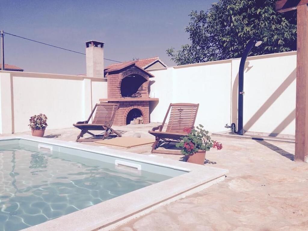 A pool area with lounge chairs and a brick oven.
