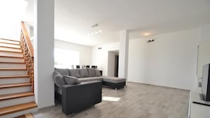 En moderne stue med en hjørnesofa, en trappe og et fladskærms-tv.