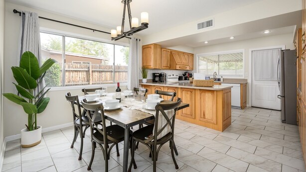 A spacious kitchen with wooden cabinets, a dining table set for four, and a large window providing natural light. - Cozy, private getaway with pool (Mesa)