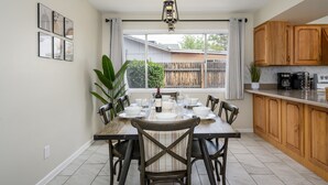 A dining area with a table set for four, a chandelier, and a view of the backyard through a large window. - Cozy, private getaway with pool (Mesa)