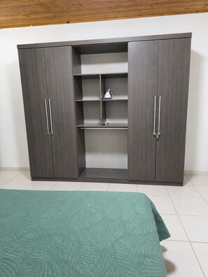 Vaatekaappi, jossa on kaksi ovea, keskellä oleva hylly ja vaatetanko.