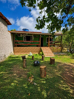 Una casa con facciata verde, tetto in tegole e un portico con gradini che conducono all'ingresso.