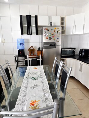 Una cucina moderna con mobili bianchi, un frigorifero in acciaio inossidabile, un forno a microonde e un forno elettrico.