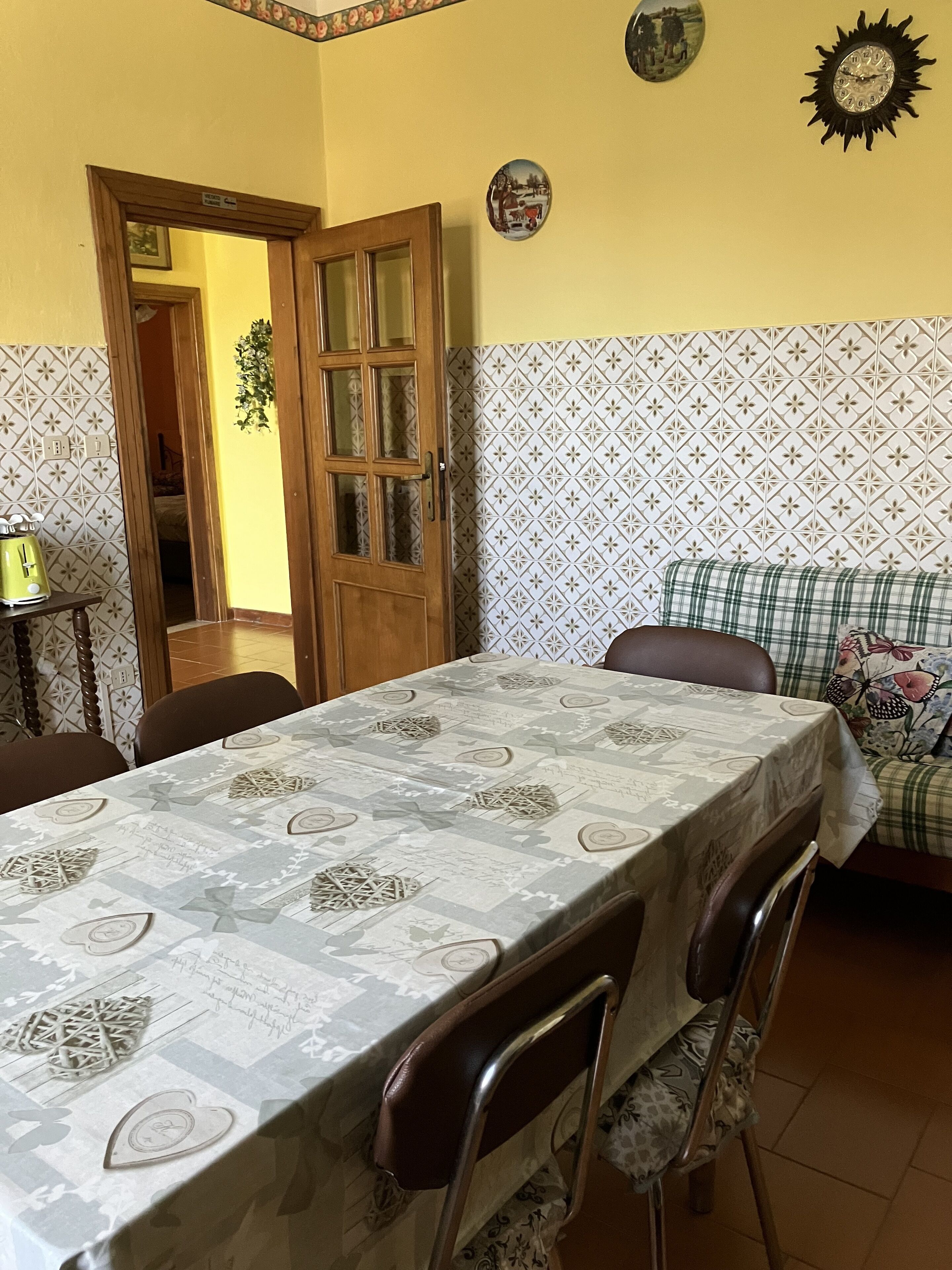 Un coin repas avec une table recouverte d’une nappe à motifs, entourée de chaises.