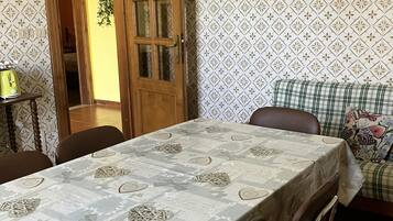 Un coin repas avec une table recouverte d’une nappe à motifs, entourée de chaises.