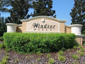 A sign for Windsor Hills with a landscaped foreground and trees in the background.