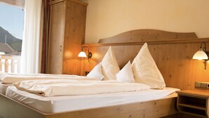 Un lit en bois avec une literie blanche, deux lampes fixées au mur et une table de chevet en bois.