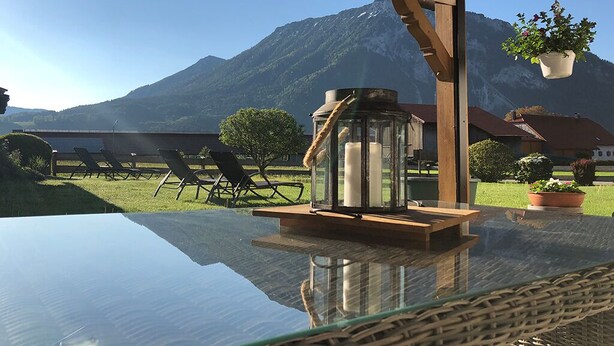 Une table avec un plateau en verre, une lanterne, des chaises et une vue sur les montagnes.
