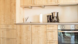 Une cuisine avec des meubles en bois, une cuisinière en acier inoxydable et une machine à café.