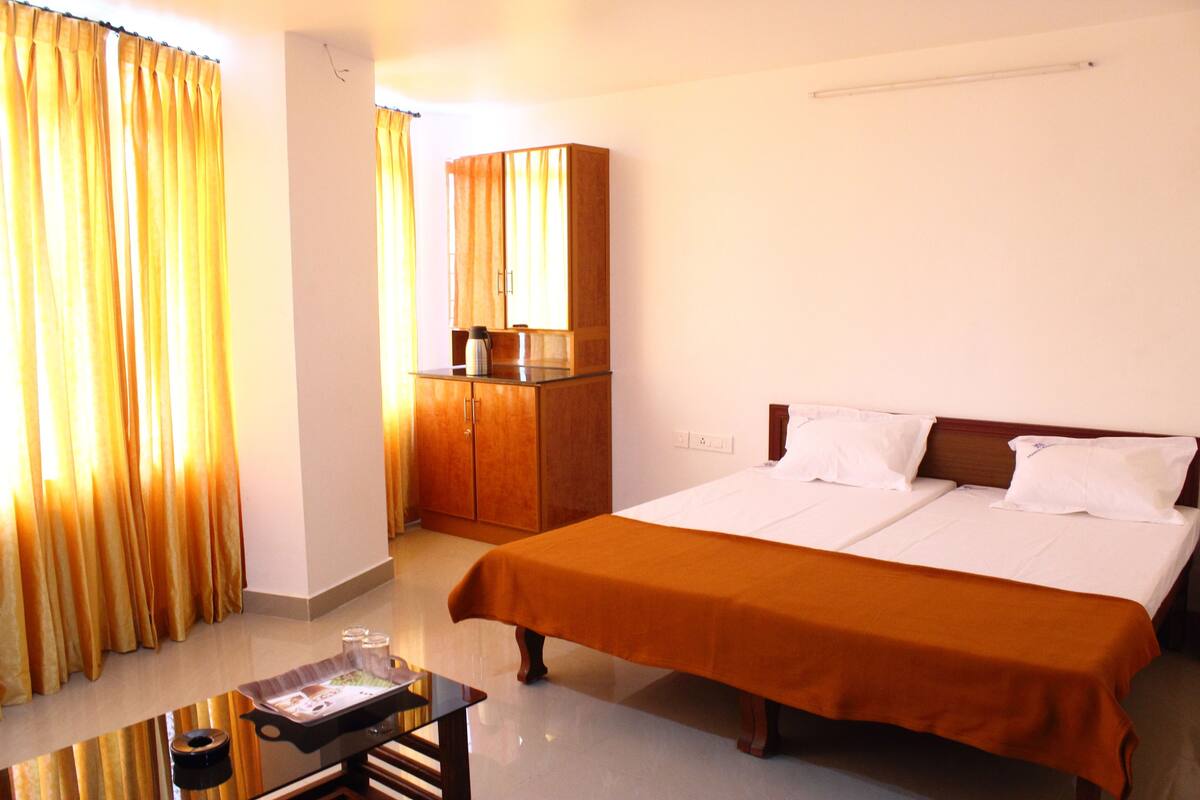A hotel room with a large bed, a wooden wardrobe, and a small table with a tray.