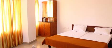 A hotel room with a large bed, a wooden wardrobe, and a small table with a tray.