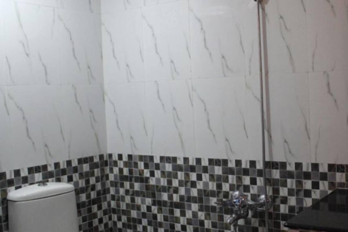 A bathroom with a toilet, a shower, and a tiled wall.