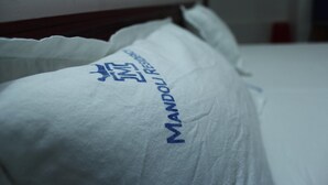 Un almohadón blanco con letras azules sobre una cama.