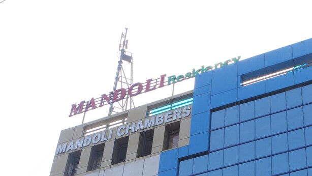 Un edificio con un letrero que dice "MANDOLI RESIDENCY" y "MANDOLI CHAMBERS".