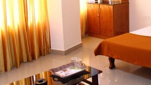 Habitación de hotel con cama, armario de madera, una mesita con bandeja y cortinas.