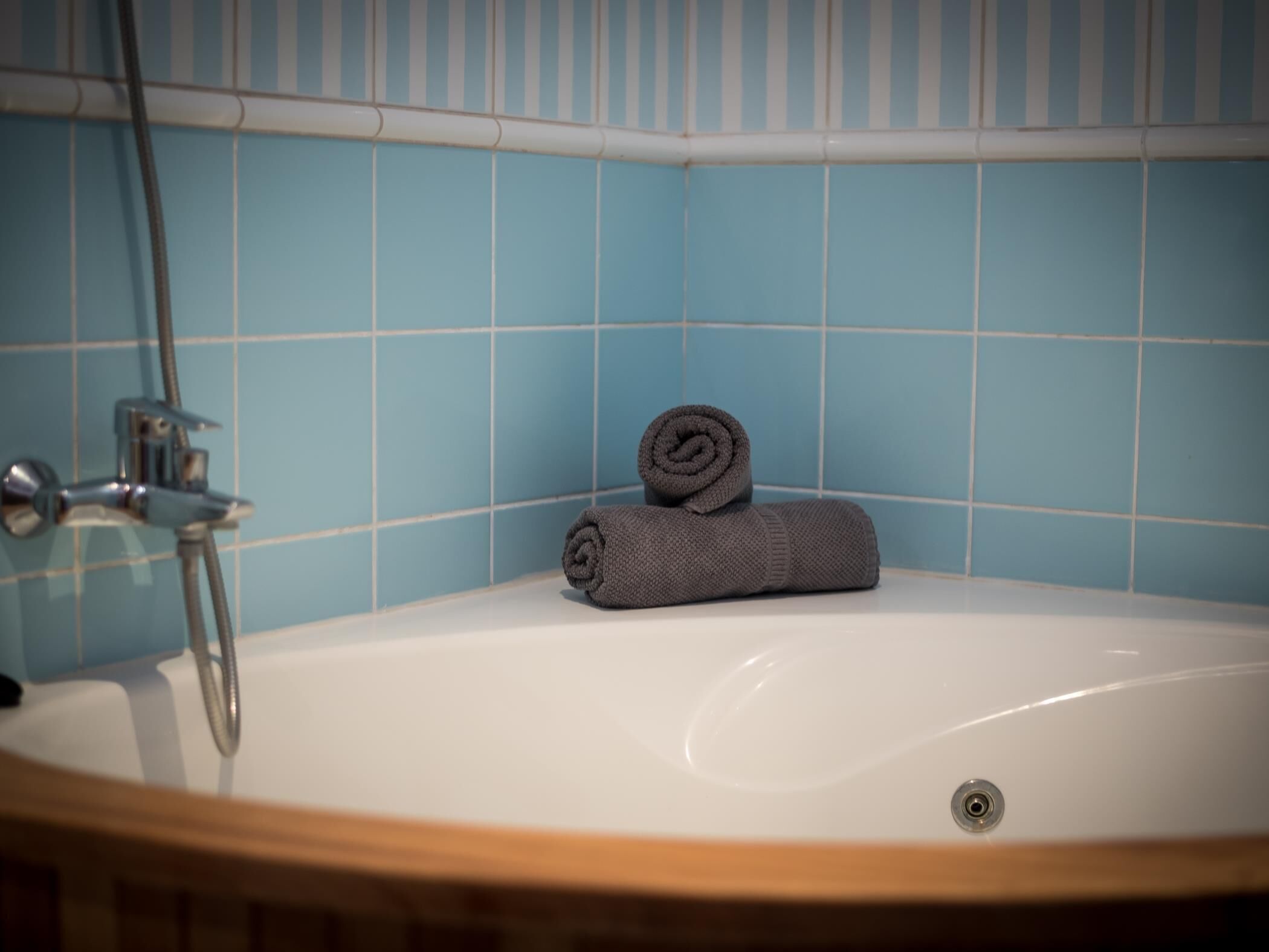 A bathroom with a bathtub, a towel, and a shower head.