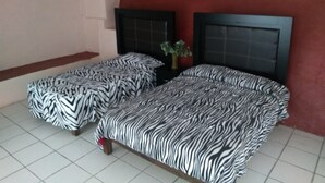 Habitación con dos camas, cada una con ropa de cama a rayas de cebra. La pared es roja y el techo, blanco.