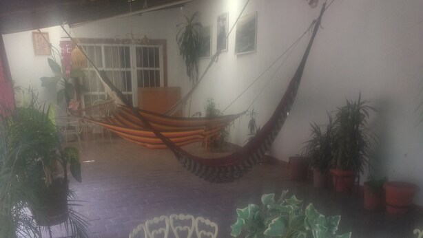 Un patio con una mesa redonda y sillas, rodeado de plantas en macetas.