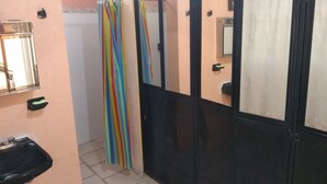 Un baño con puerta negra, espejo, lavabo y cortina de ducha.