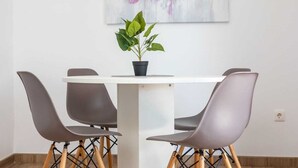 A dining area with a white table and four grey chairs with wooden legs. A potted plant is on the table. - Apartment LaPePa (Silo - island Krk)