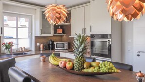 Una cucina moderna con isola centrale, elettrodomestici in acciaio inossidabile e una ciotola decorativa piena di frutta.