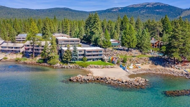 A coastal hotel with multiple buildings, a clear view of the surrounding forest, and a rocky shoreline. - Ideal Couple, Small Family Getaway, Lakefront Complex w/ Private Beach/Pool by Tahoe Time VR (Tahoe Vista)