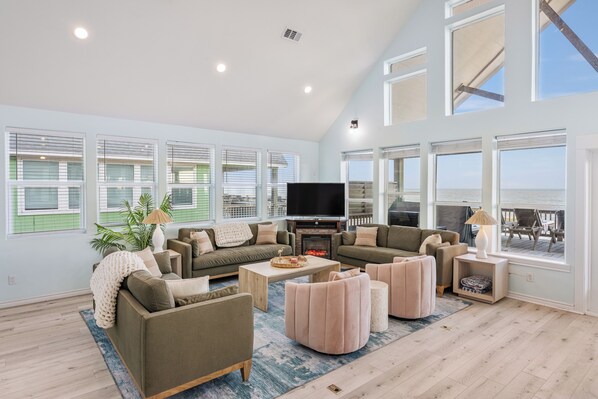 A spacious living room with a fireplace, large windows, and a balcony with outdoor furniture.