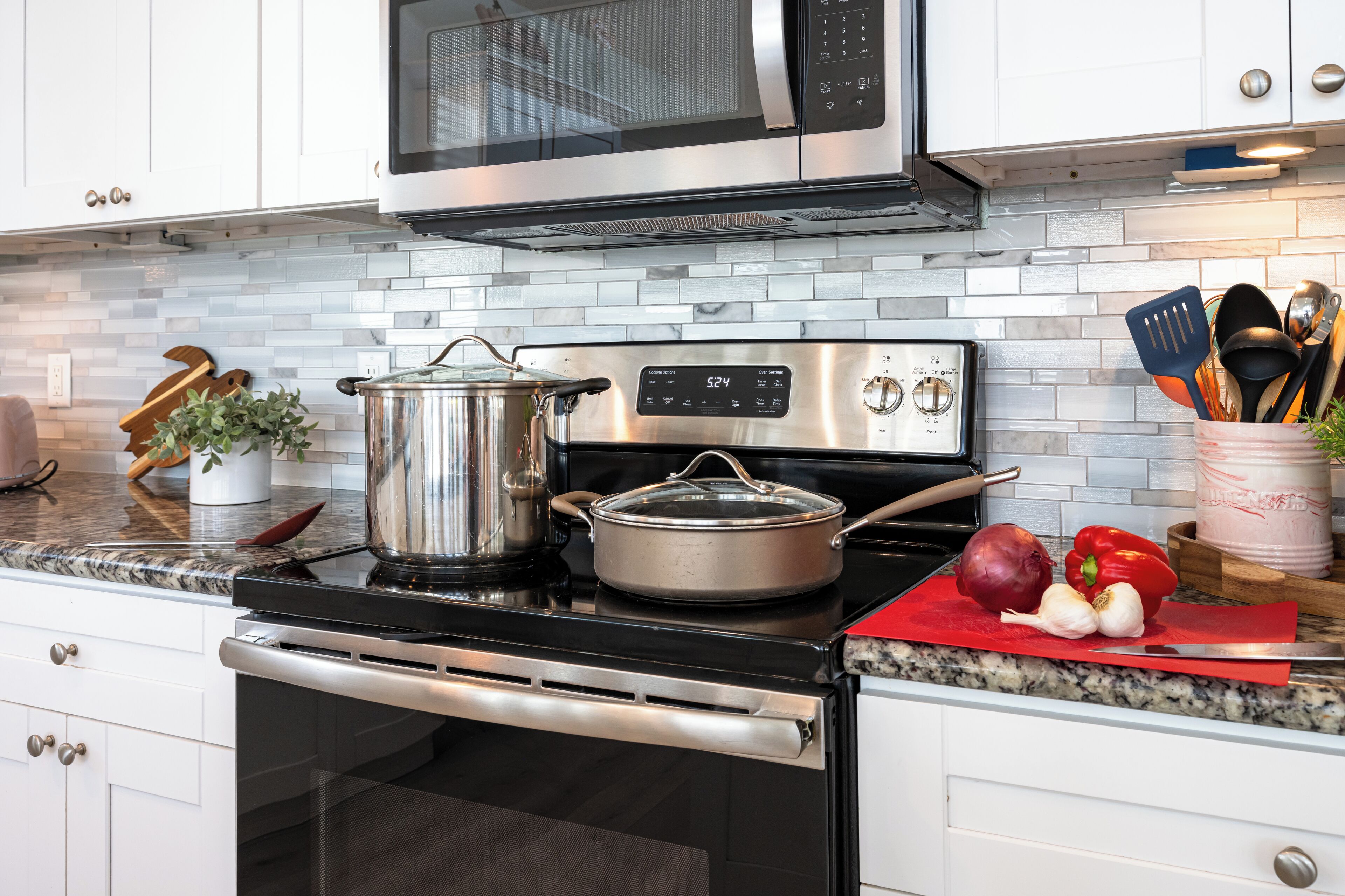 A modern kitchen with stainless steel appliances, a microwave, and a tiled backsplash.