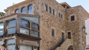 A stone building with multiple windows and a staircase leading to an upper level. - Luxury Rocamar – Beachfront & Terrace (Tossa De Mar)