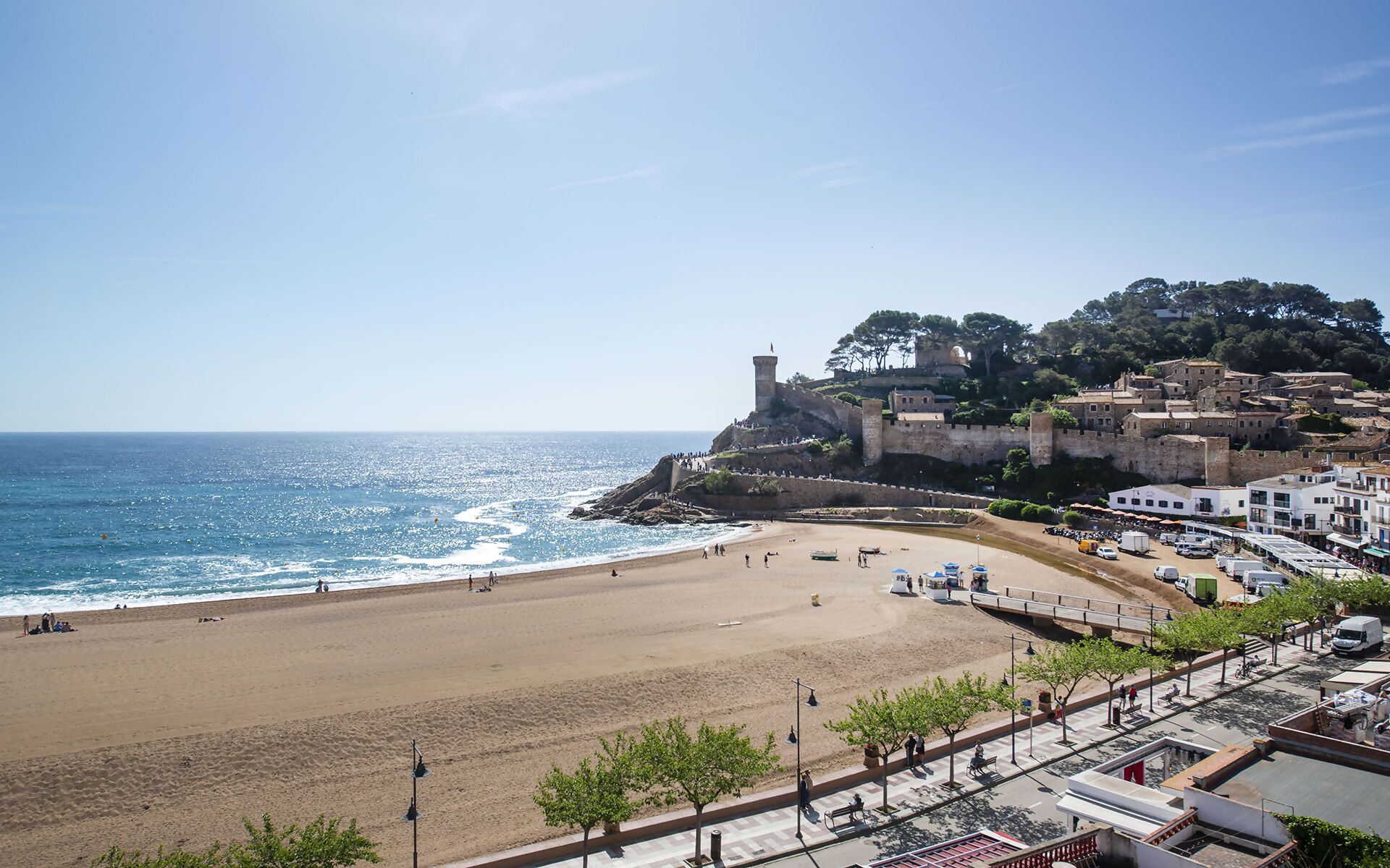 A coastal town with a beach, a fortified structure, and a mix of residential and commercial buildings.