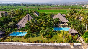 Ein Resort mit strohgedeckten Bungalows, einem Schwimmbad und üppigen tropischen Gärten.