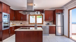 A modern kitchen with wooden cabinets, stainless steel appliances, and a large window. - 2.Charming Villa Private Pool and sea view (Adeje)