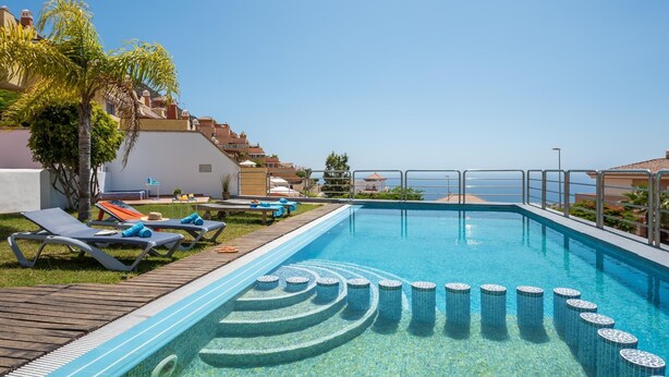 A swimming pool with a tiled design, surrounded by lounge chairs and a view of the sea. - 2.Charming Villa Private Pool and sea view (Adeje)